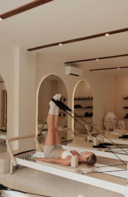 Alumna elongando piernas en el reformer del estudio